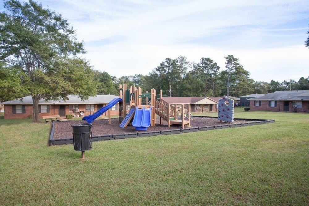 A playground with slides, climbing wall, and trashcan