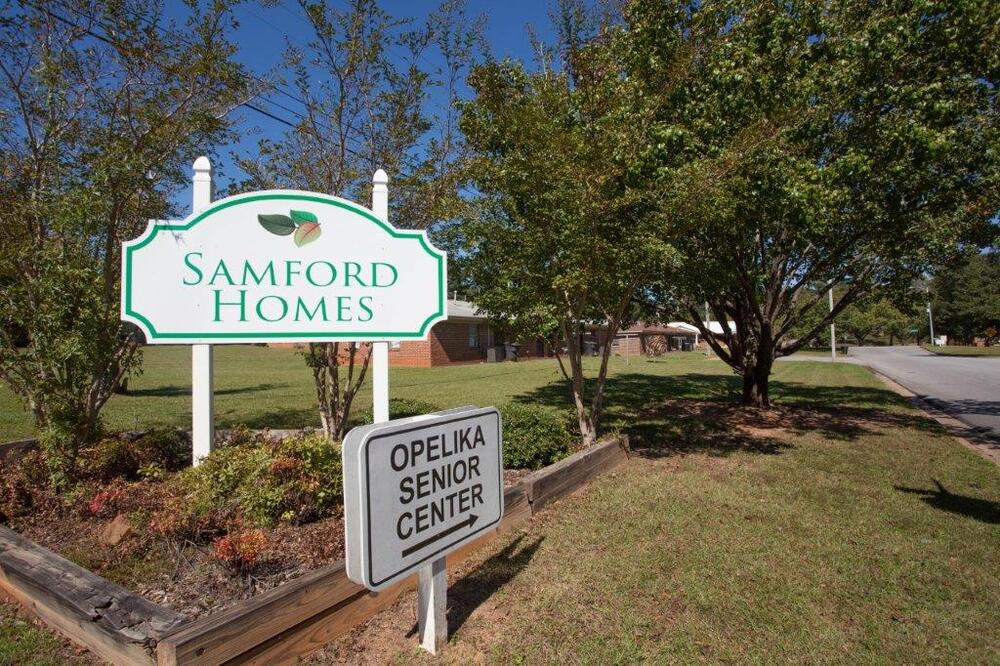 Signs that read Samford Homes and Opelika Senior Center with an arrow pointing towards a building 