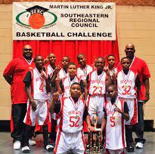 A basketball team standing in front of a banner that reads 